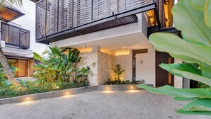 Ein modernes Gebäude mit einer Steinfassade, einem Balkon mit Metallgeländern und einem gepflasterten Innenhof mit Pflanzen.