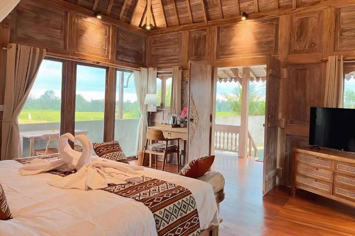 A spacious bedroom with a large bed, a desk, and a television.