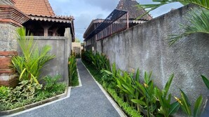 A narrow pathway flanked by lush greenery and traditional buildings with tiled roofs. - Gunung Gelagah Ubud Villas by EPS (Tegallalang)
