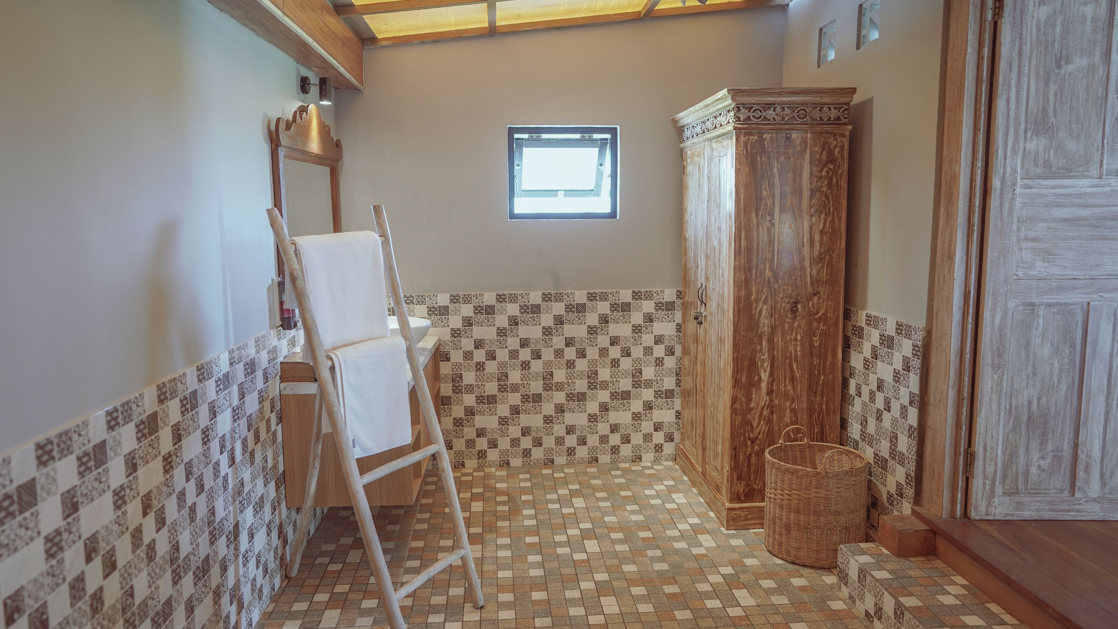 Een badkamer met betegelde vloer, een houten kast, een raam en een ladder.