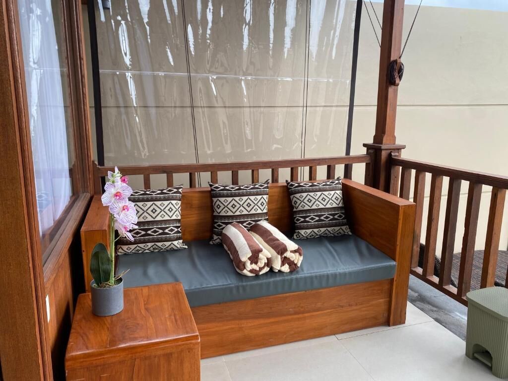 A wooden bench with patterned cushions and a small potted orchid.