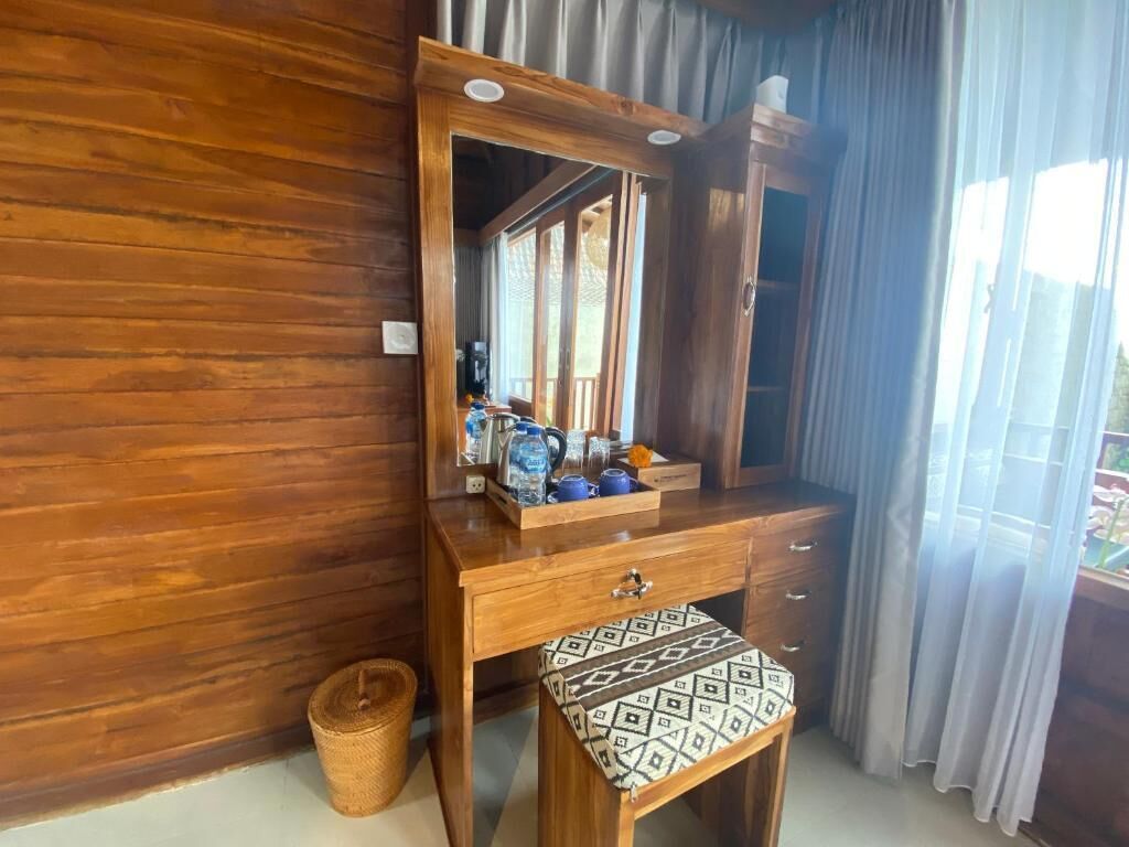 A wooden vanity with a mirror, a small stool, and a tray with toiletries.
