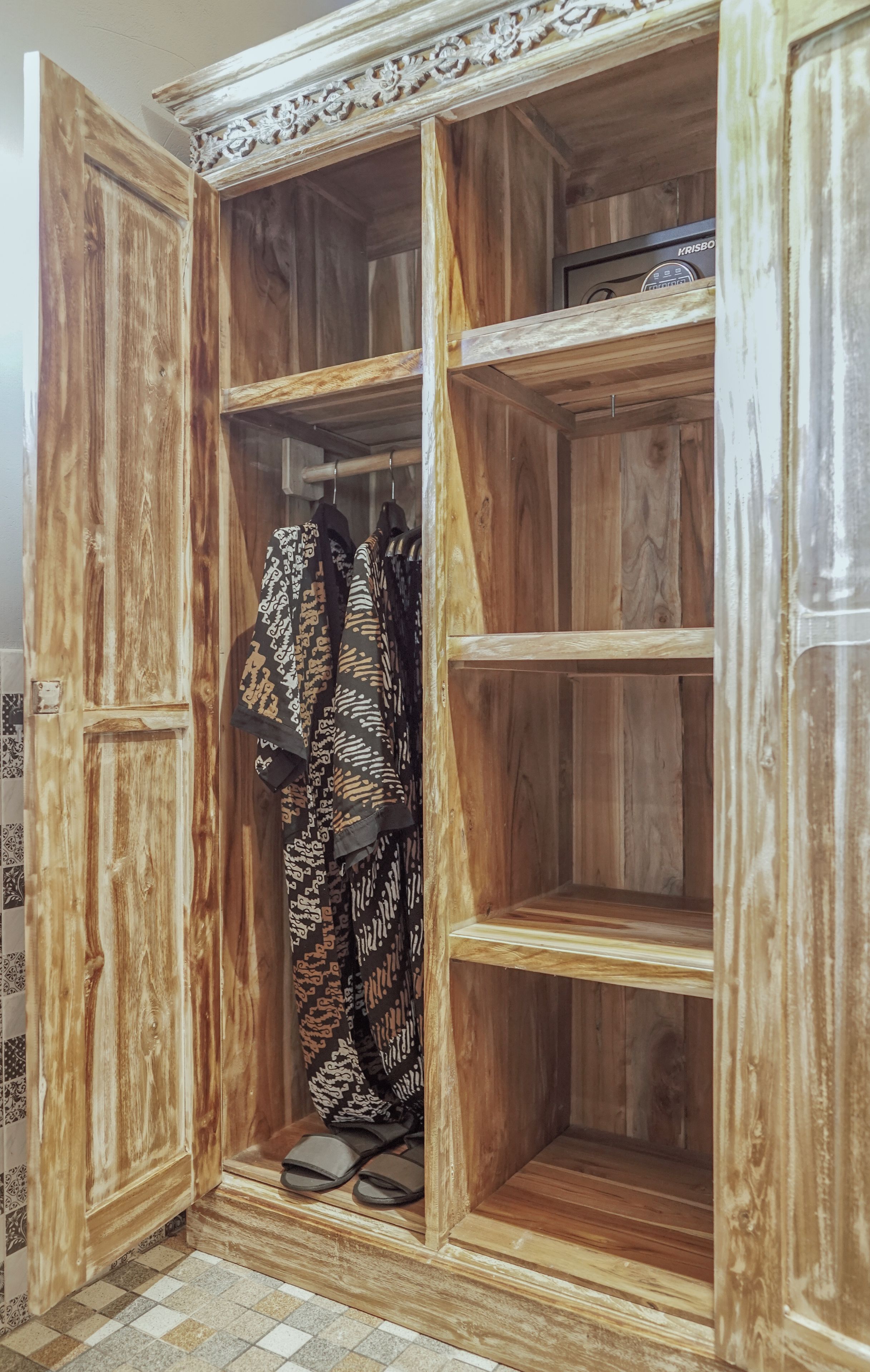 A wooden wardrobe with a mirrored door, a hanging rack, and a shoe shelf.