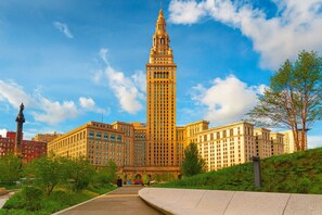 Un grand bâtiment historique, doté d’une tour imposante, entouré de verdure et d’autres constructions.