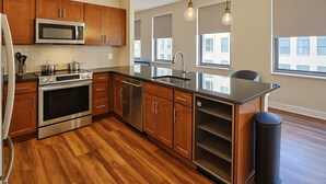 A modern kitchen with wooden cabinets, stainless steel appliances, and a large island. - Downtown Suite - Spacious! RnRHoF, Casino, Stadium (Cleveland)