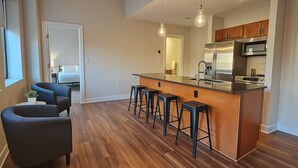 A modern kitchen with a central island, bar stools, and wooden flooring. - Downtown Suite - Spacious! RnRHoF, Casino, Stadium (Cleveland)
