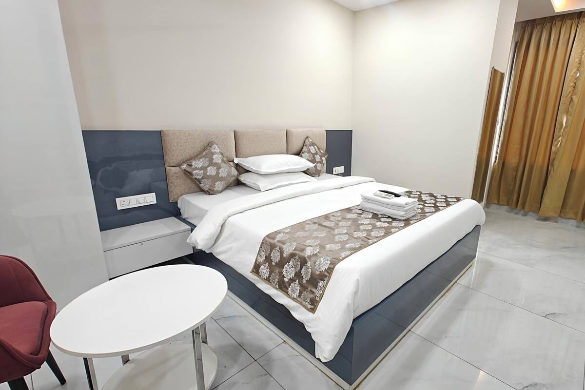 A modern hotel room with a bed, bedside table, and a small round table.