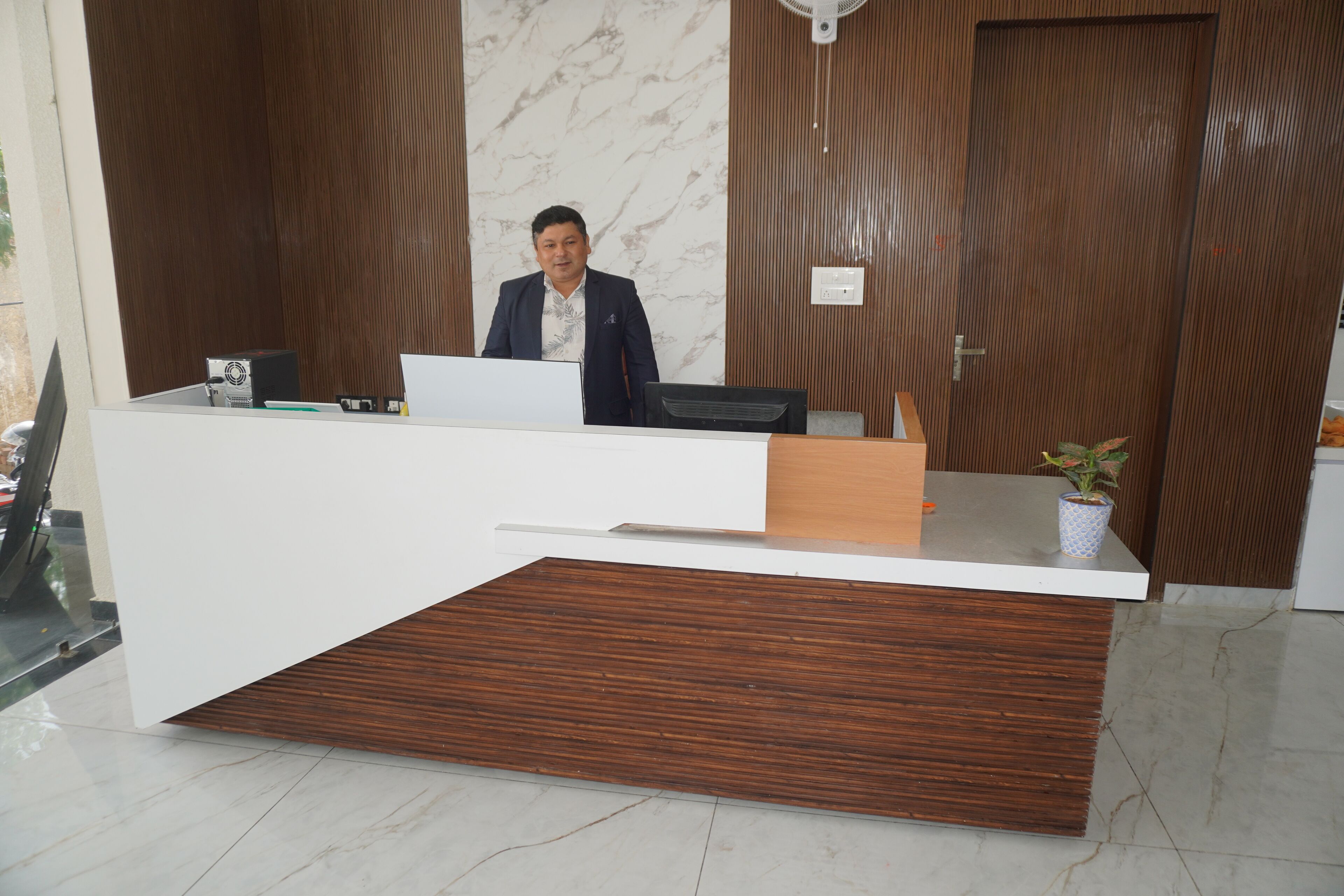 A reception desk with a modern design, featuring a wooden panel and a white counter.
