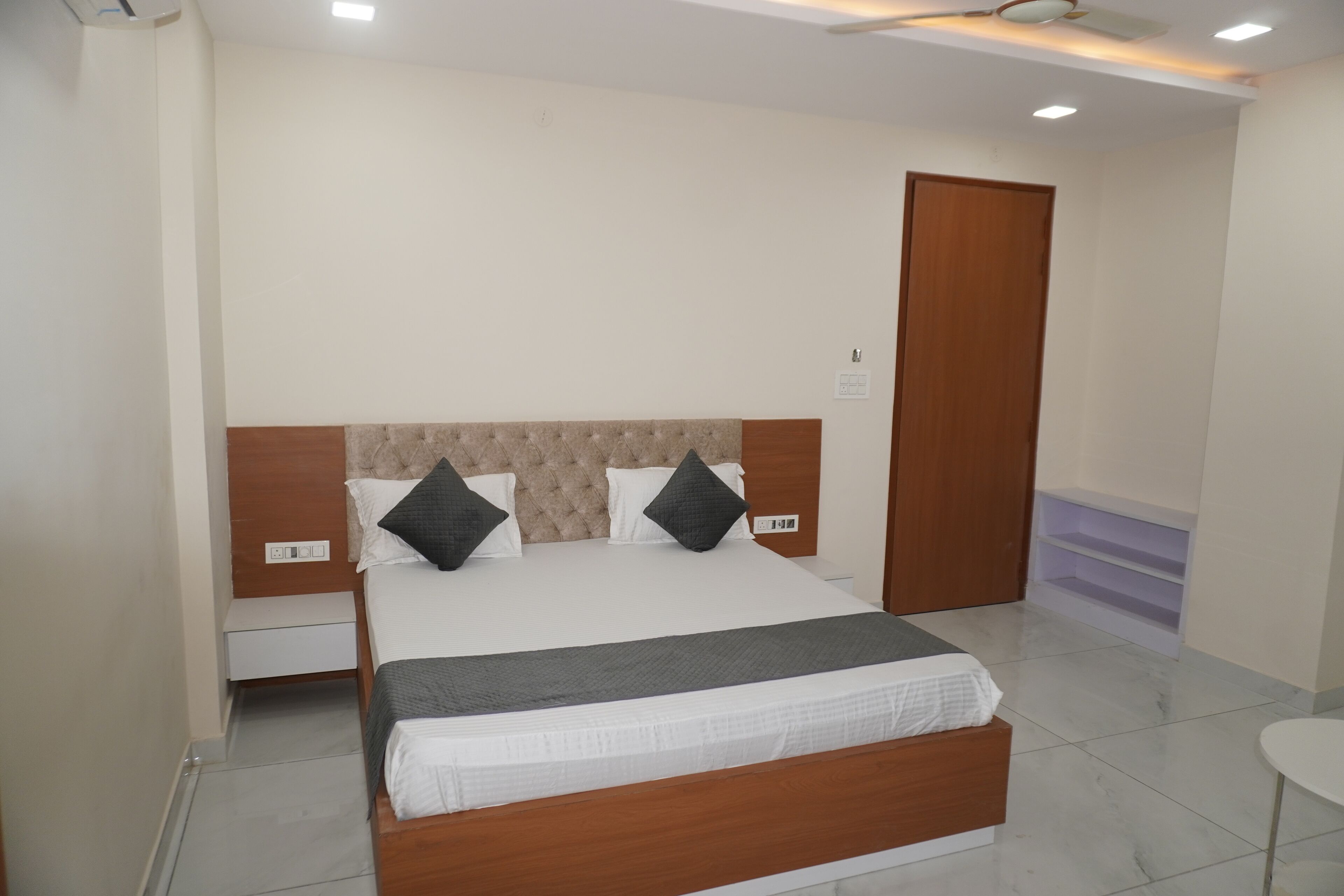 A neatly arranged bedroom with a large bed, a wooden headboard, and a bedside table.