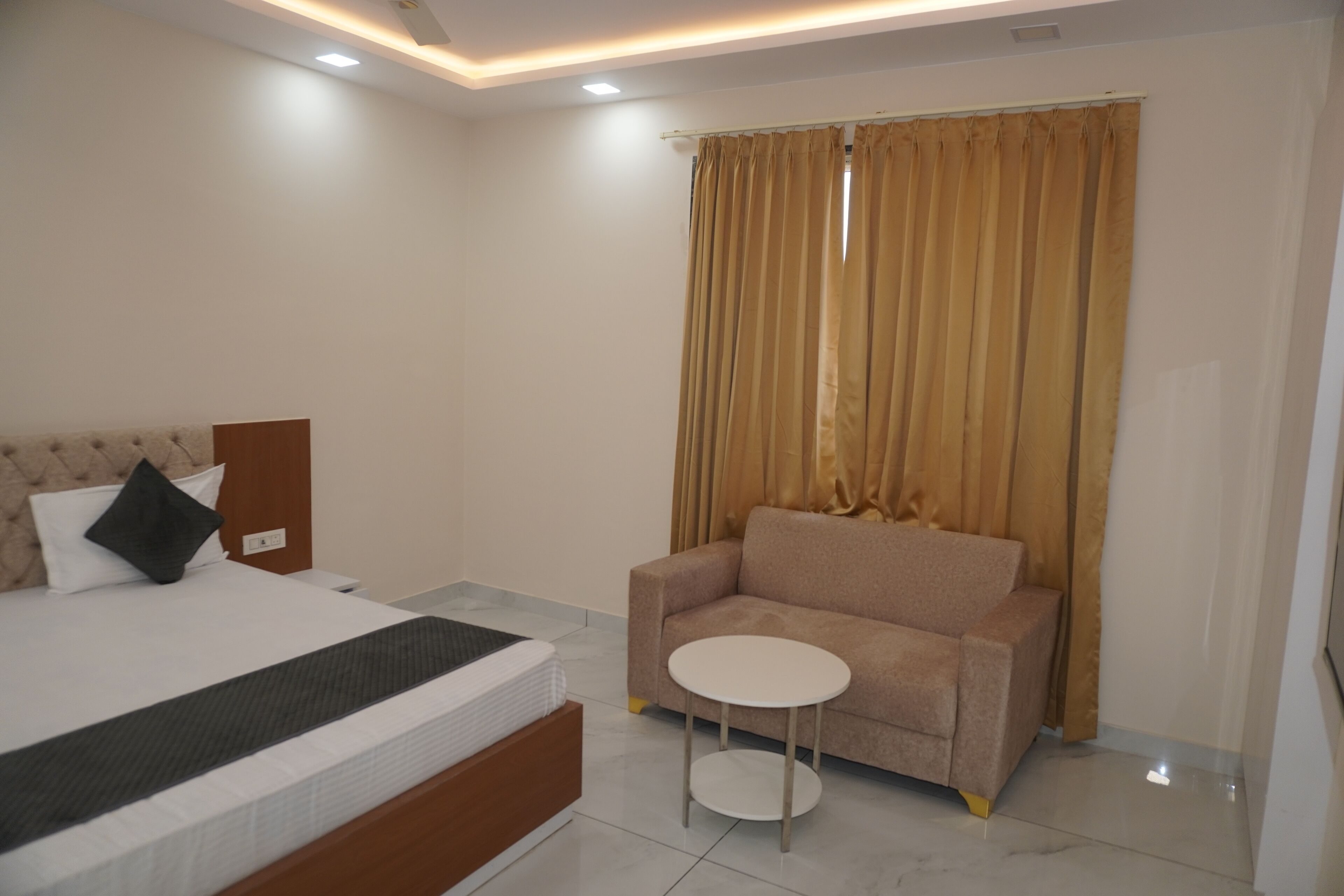 A bedroom with a bed, a sofa, and a small table.