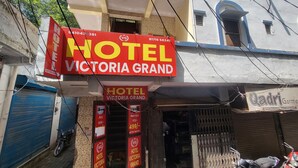 Une enseigne d’hôtel pour le Victoria Grand, avec une entrée bien visible et un chien que l’on aperçoit à l’intérieur.