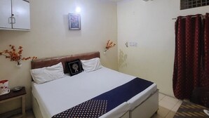 Une chambre à coucher comprenant un lit, une table de chevet, un ventilateur de plafond, une fenêtre avec des rideaux et un meuble fixé au mur.