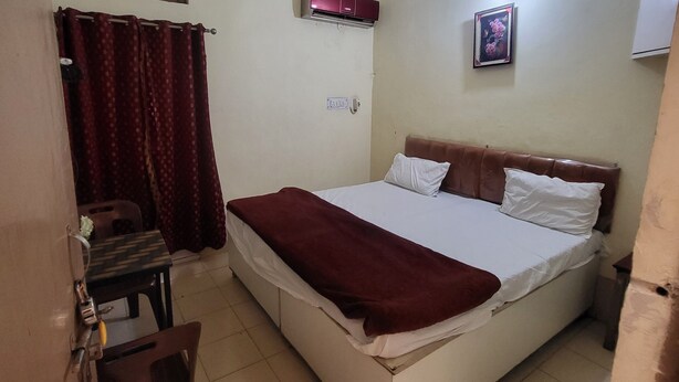 Une petite chambre à coucher, de taille réduite, comprenant un lit simple, un bureau et une chaise.