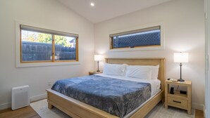 Una camera da letto con un letto, due comodini con lampade, una finestra e un termosifone.