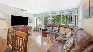 A living room with a brown leather sofa, a wooden dining table, and a flat-screen TV. - Suntastic -  Salt Water Lagoon Front 2 Bedroom in popular OCEAN FRONT Kawama (Key Largo)