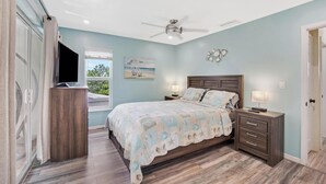 A bedroom with a bed, bedside tables, a ceiling fan, a window with a beach view, and a TV on a stand. - Suntastic -  Salt Water Lagoon Front 2 Bedroom in popular OCEAN FRONT Kawama (Key Largo)
