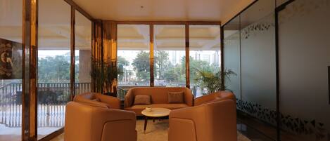 A modern lounge area with a sofa set, a coffee table, and large windows offering a view of the outdoors.