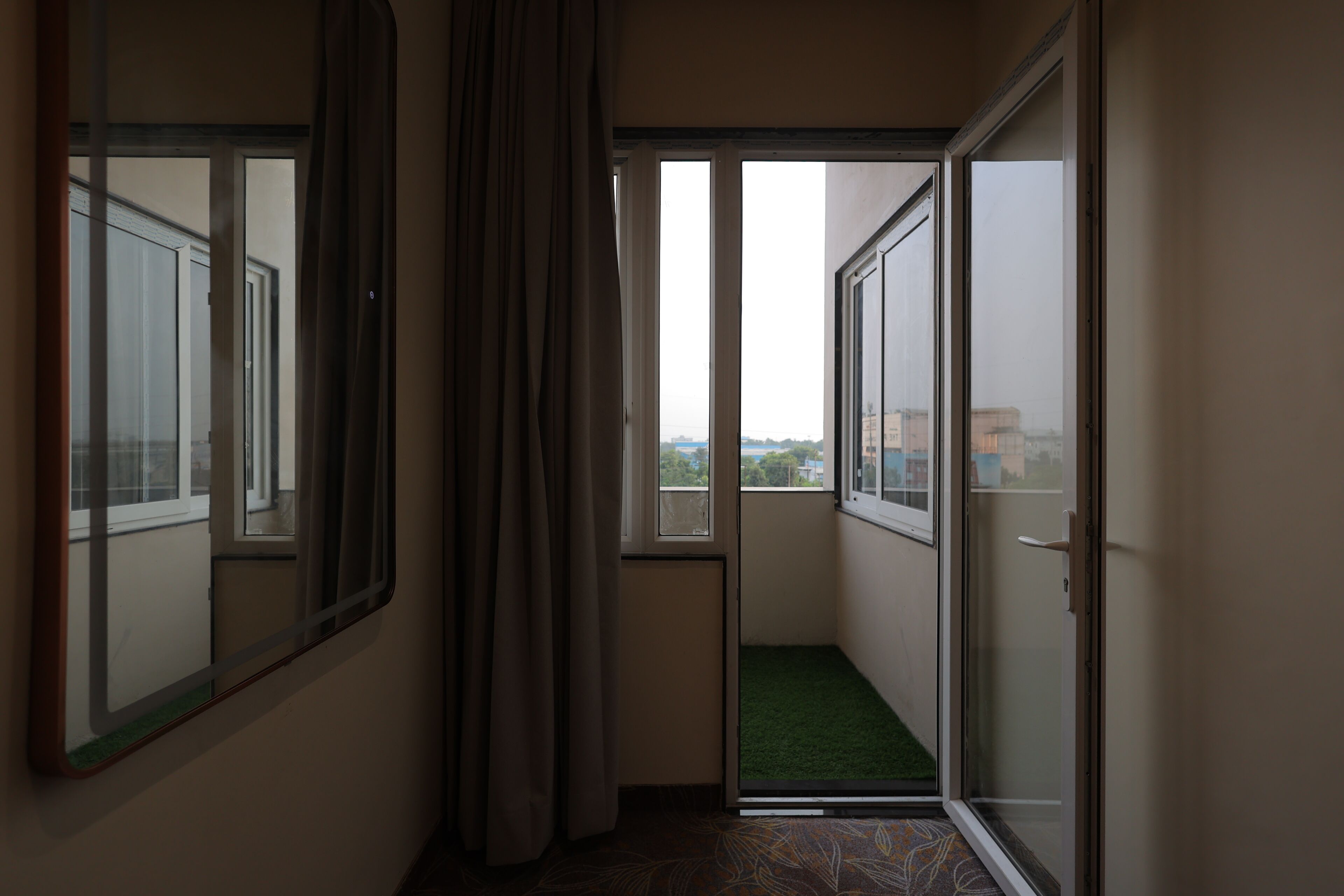 A corridor with a sliding glass door leading to a balcony with a green mat.