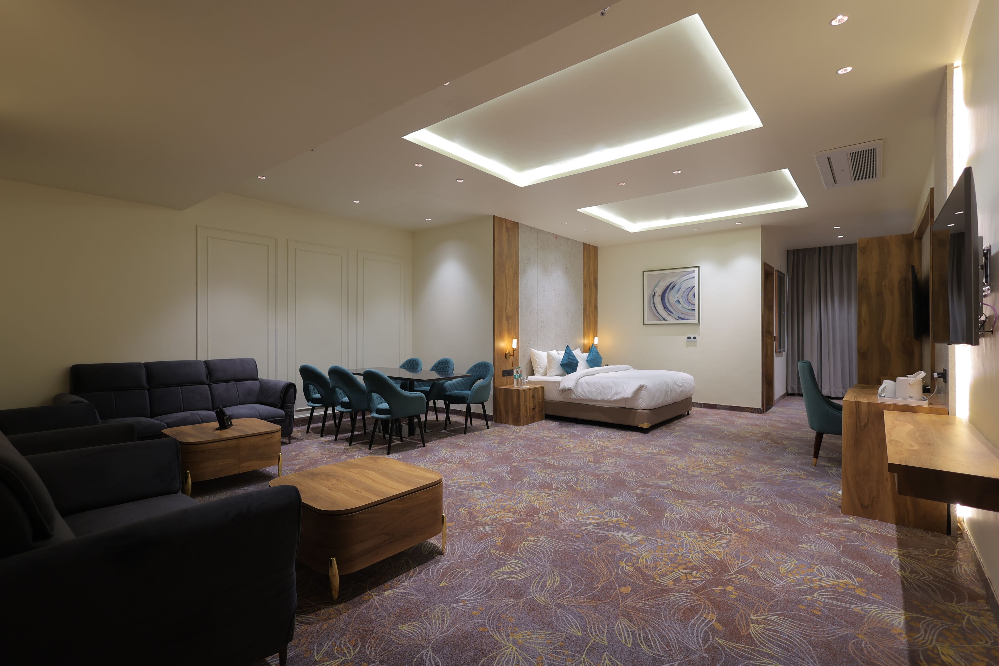 Una habitación de hotel con sofá, mesa de comedor, cama y televisor.