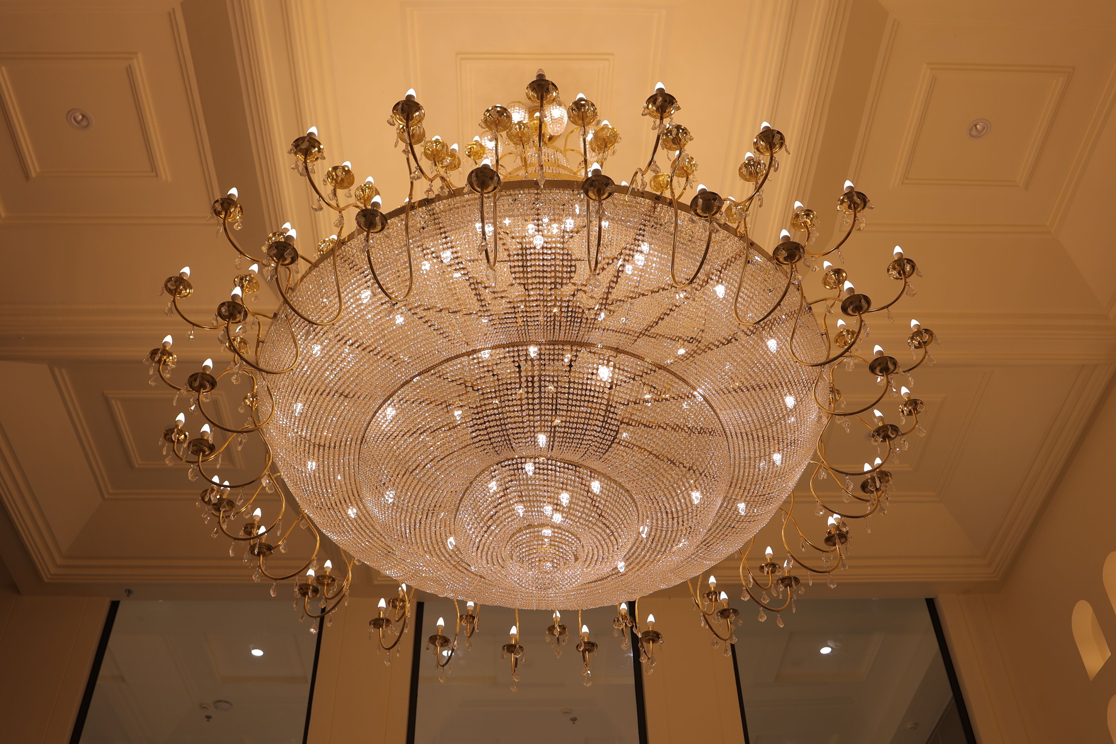 Un grand lustre somptueux, à plusieurs niveaux et doté de nombreuses sources lumineuses.