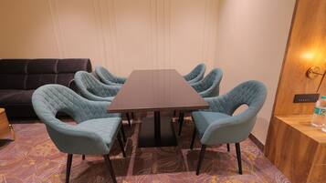 A conference room with a rectangular table, six upholstered chairs, a dark sofa, and a patterned carpet.