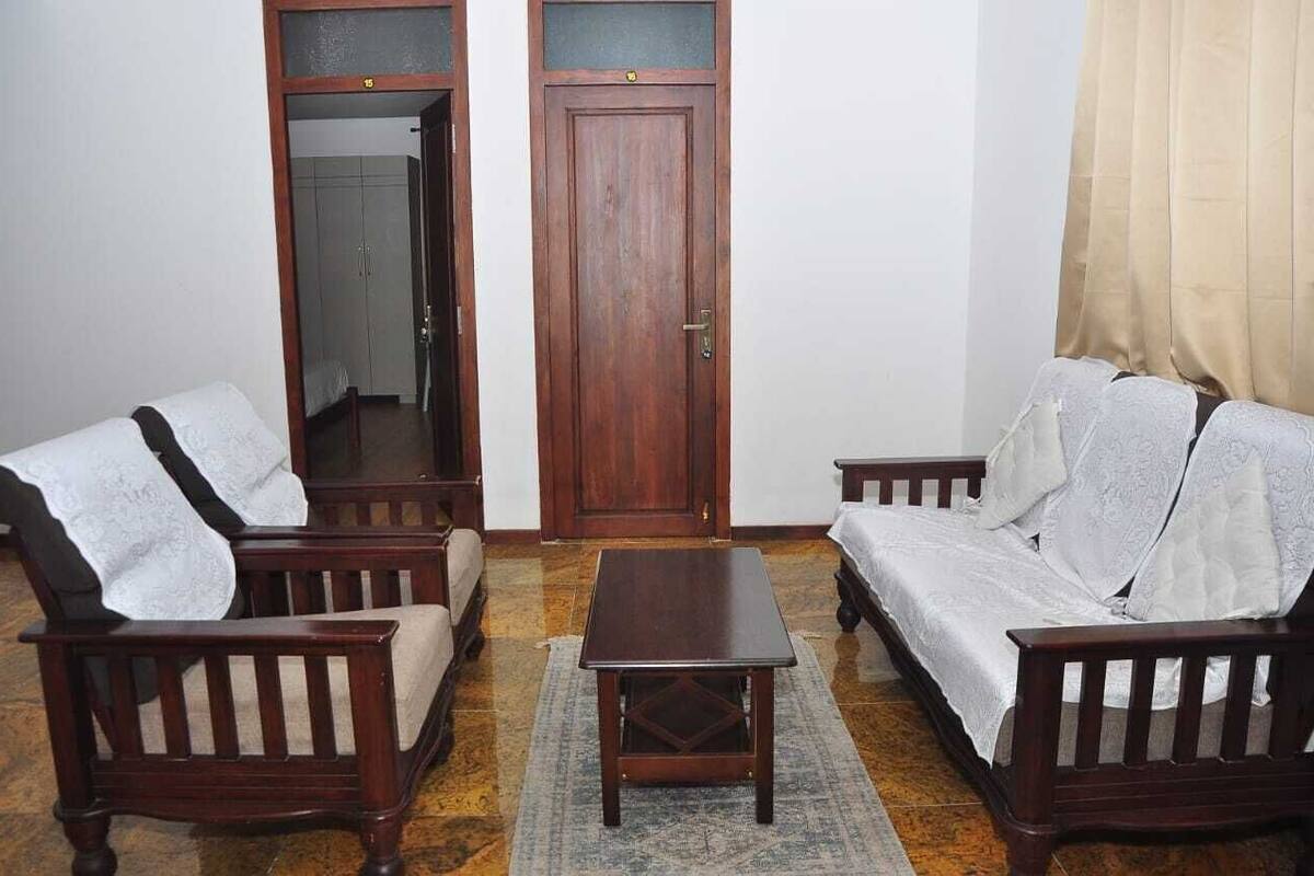 A room with two wooden sofas, a small wooden table, and a door with a number above it.