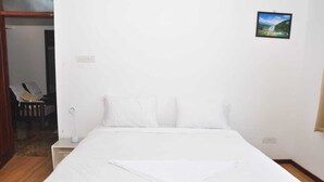 A hotel room with a large bed, a bedside table with a lamp, and a small picture on the wall. - Srivari Studio Apartment (Kodaikanal)