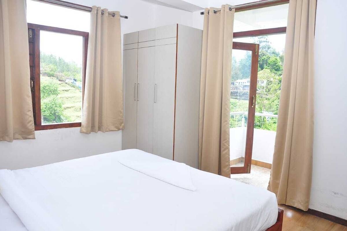 A bedroom with a bed, a wardrobe, and a sliding glass door to a balcony.