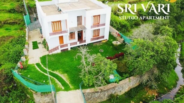A modern two-story studio apartment with a flat roof, surrounded by lush greenery and a small stream. - Srivari Studio Apartment (Kodaikanal)
