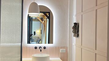 A compact bathroom with a white sink, a mirror, and a wooden ceiling.