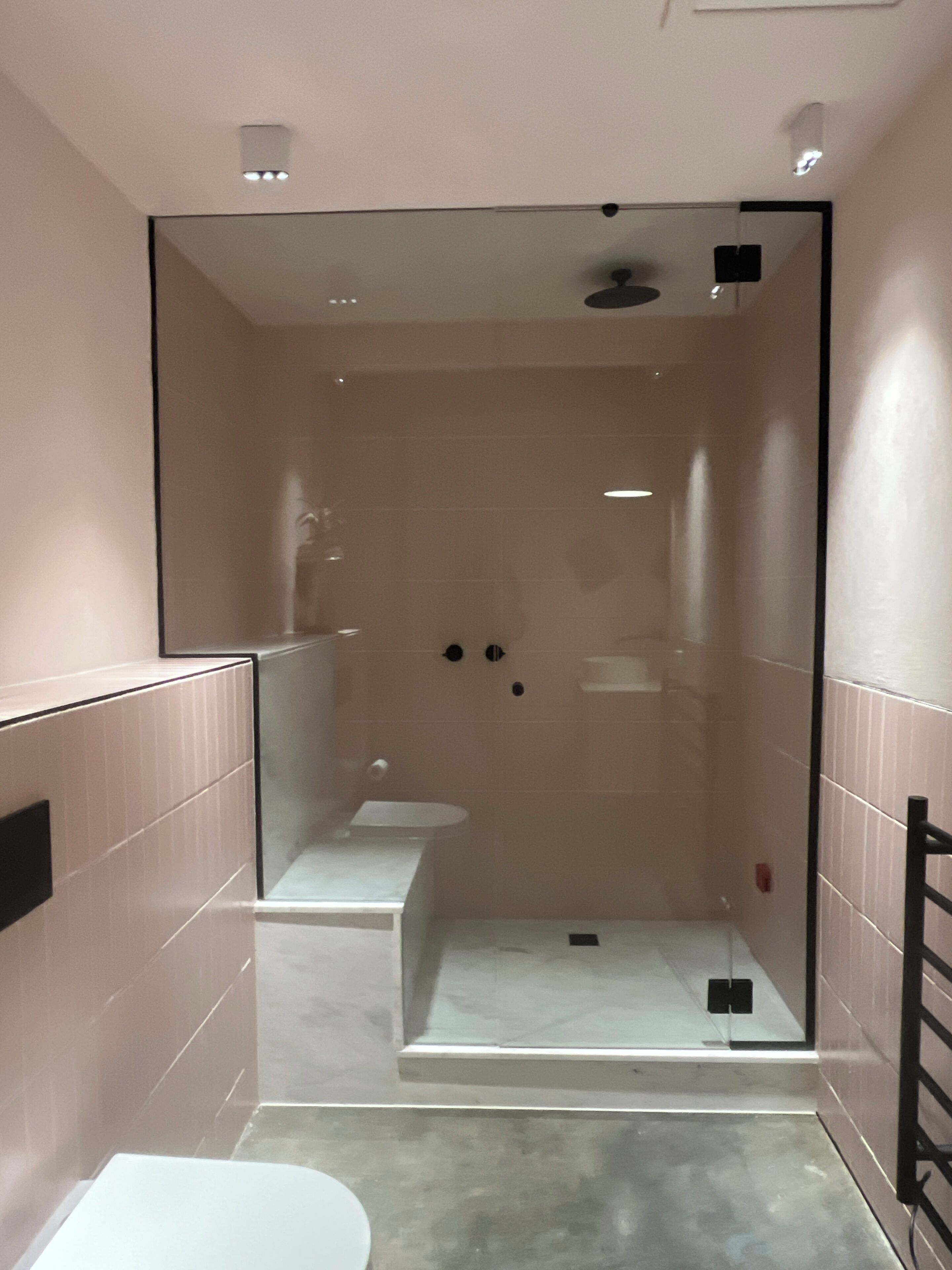 Een moderne badkamer met een douchecabine van glas, een toilet en een wastafel.