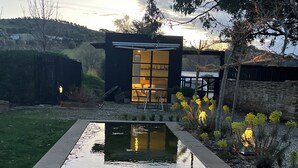 A modern outdoor pool area with a clear view of a building with large windows and a patio. - The Barn at Stonewalls - Farm stay in 25 acres In Daylesford (musk)