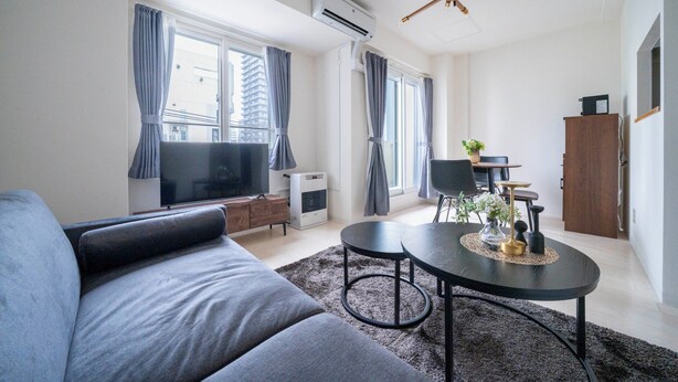 A modern living room with a grey sofa, a round coffee table, and a flat-screen TV. - BELLE NEIGE 401 (Sapporo)