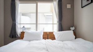 A neatly made bed with white linens, a wooden headboard, and two bedside lamps. - BELLE NEIGE 401 (Sapporo)