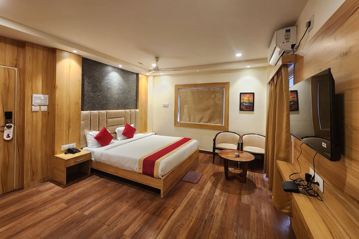 Habitación de hotel con cama de madera, mesitas de noche, televisión y ventana con vistas.