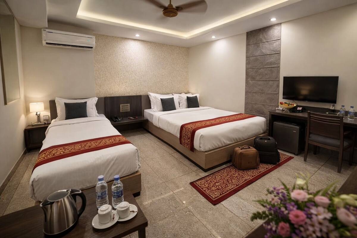 A hotel room with two beds, a desk, a television, and a minibar.