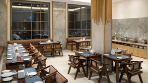 A restaurant with long wooden tables and chairs, marble walls, and large windows. - OPO Horizon Surbhi Grant,Khatu Shyam (Danta Ramgarh)