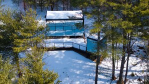 Una cabana amb un teulat cobert de neu, envoltada d'arbres.