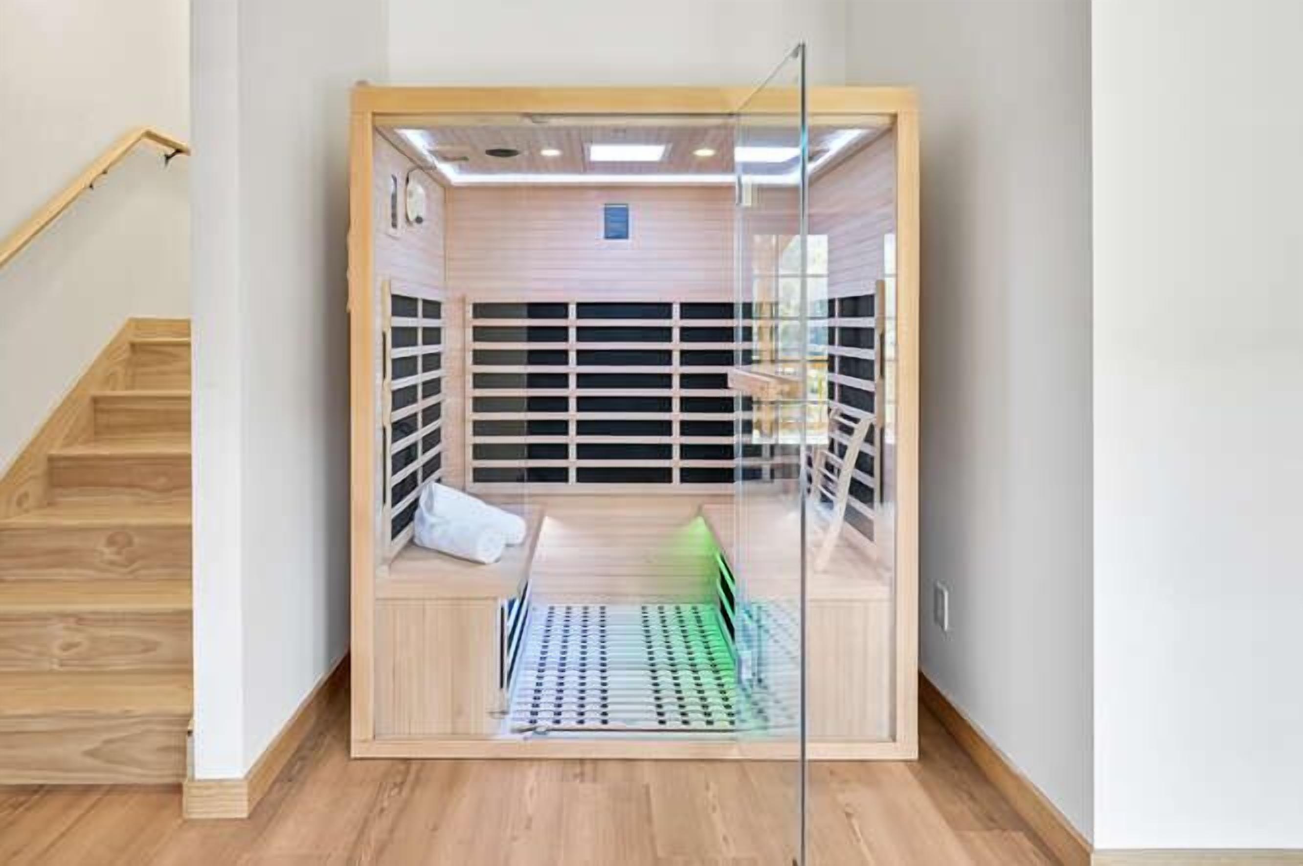 A compact, enclosed room with a wooden floor, a glass door, and a small bench.