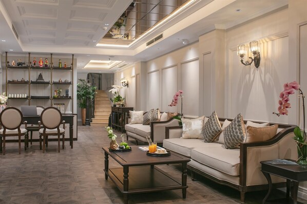A spacious living room with a sofa, coffee table, and a bookshelf. - Bespoke Boutique Hotel Hanoi (Hanoi)