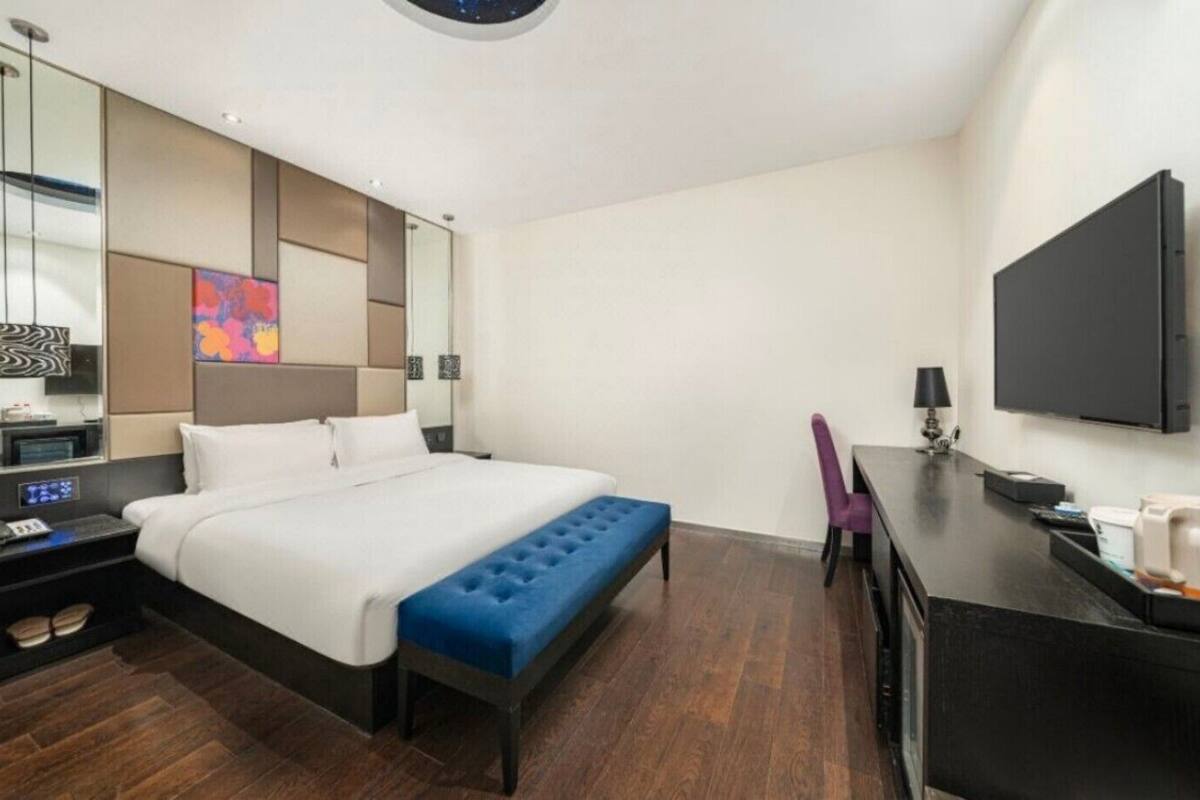 Une chambre d’hôtel équipée d’un lit, d’un bureau, d’une chaise, d’une télévision et d’une table de chevet.