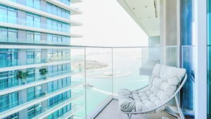 A high-rise building with multiple balconies, a glass railing, and a view of a body of water. - Beach Isle Residences- Emaar Beachfront (Dubai)
