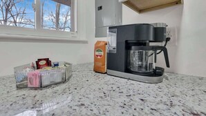 A kitchen with a coffee maker, a coffee bean bag, and a spice rack on the counter. - The Penick Getaway Su (Reynoldsburg)