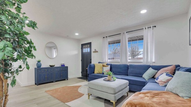 A modern living room with a blue sofa, a grey ottoman, and a blue cabinet. - The Penick Getaway Su (Reynoldsburg)