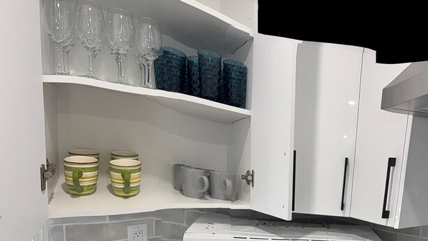 A kitchen with white cabinets, a microwave, and shelves holding glasses and jars. - Beautiful Renovated Bi-level  Home close to shopping, transit, & Rec Centre (Calgary)