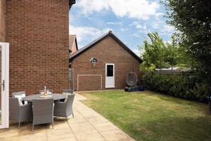 Eine Terrasse mit Korbmöbeln und einem Basketballkorb in einem Garten.