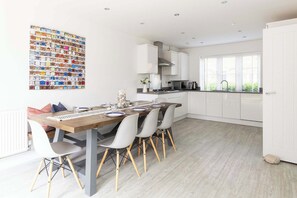 Eine moderne Küche mit weißen Schränken, einem Holztisch und einem großen Fenster.