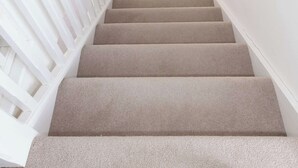 A staircase with beige carpeted steps and white railings, leading to a room with a window and a radiator. - Modern Family Retreat Nr Beaches and Marina (Birdham)