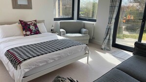 A bedroom with a bed, a chair, a sofa, a window, and a radiator.