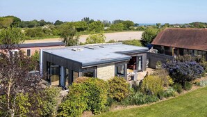 A modern house with a flat roof, large windows, and a garden.